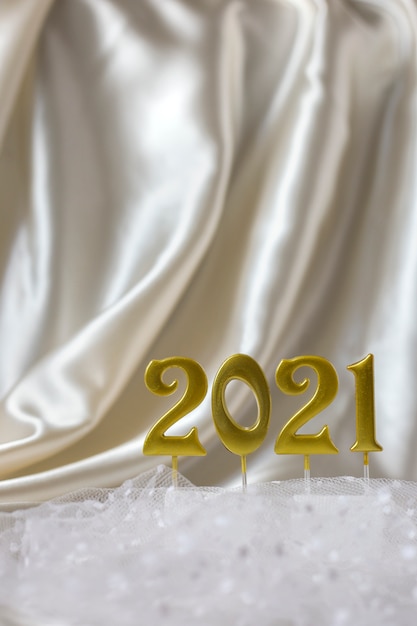 Inschrift der goldenen zahlen 2021 auf hintergrund beiger seidenfaldas, vertikale ausrichtung