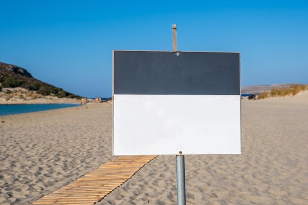 Foto inscreva-se em um quadro branco em branco em um fundo de praia de areia desfocado anunciar um modelo de espaço de cópia