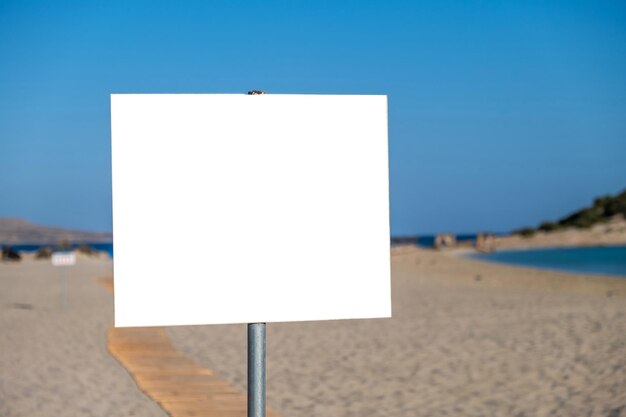 Inscreva-se em um quadro branco em branco em um fundo de praia de areia desfocado anunciar um modelo de espaço de cópia