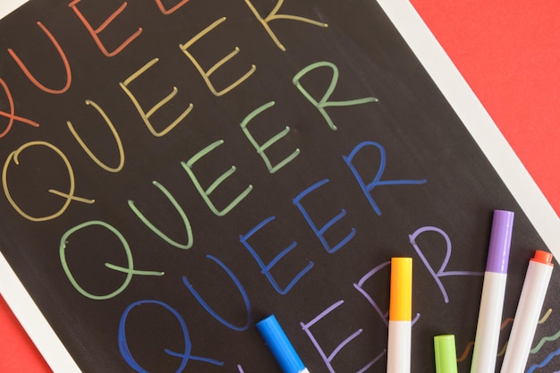 Inscrição coloful queer na placa preta sobre fundo vermelho