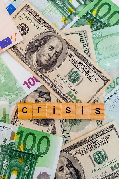 Inscrição de crise em cubos de madeira na textura de notas de dólares e euros