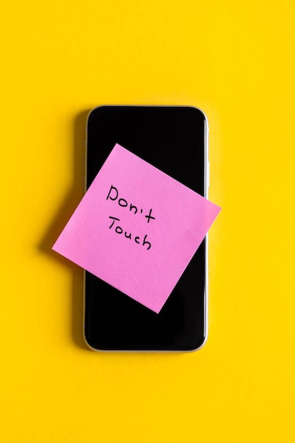 Foto inscrição não toque em um lembrete de papel na vista superior do smartphone
