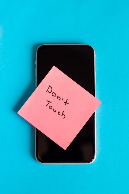 Inscrição Não toque em um lembrete de papel na vista superior do smartphone
