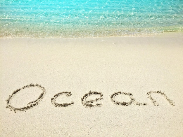 Inscrição "Oceano" na areia em uma ilha tropical, Maldivas.