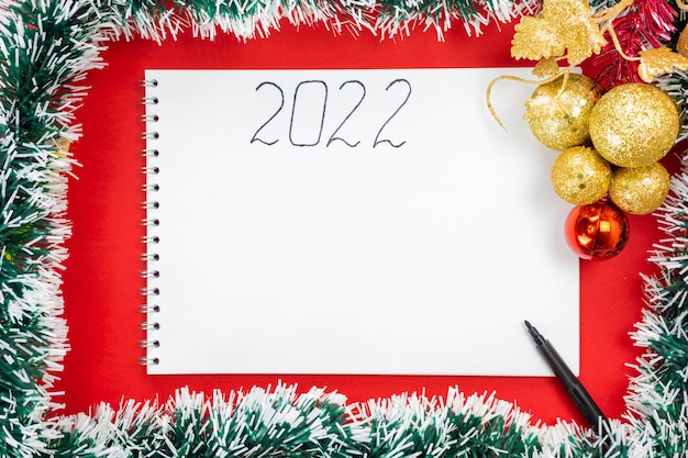 La inscripción 2022 en un cuaderno y espacio libre sobre un fondo navideño. Decoración de año nuevo.