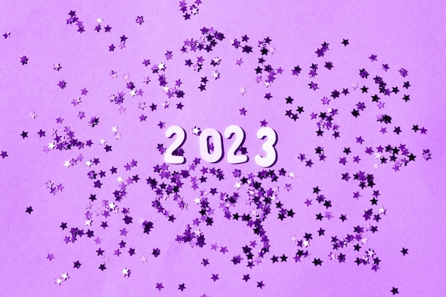 Inscripción 2023 con números de madera sobre fondo morado con confeti Concepto festivo