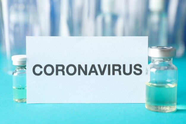 Inscripción Coronavirus y frasco de vacuna en azul, espacio para texto.