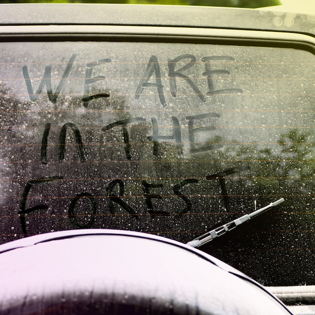 Foto inscripción en el cristal sucio y polvoriento del coche: estamos en el bosque. concepto de senderismo