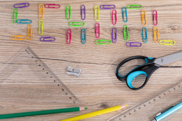 Inscripción escolar hecha de coloridos clips de papel de oficina suministros escolares básicos se encuentran en la parte superior de la