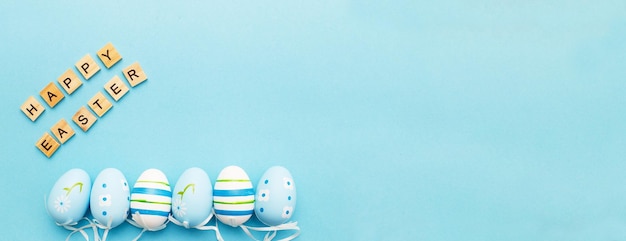 Inscripción felices pascuas con coloridos huevos pintados a mano en banner de fondo azul