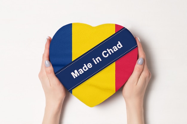 Inscripción hecha en Chad la bandera de Chad. Manos femeninas que sostienen una caja en forma de corazón.