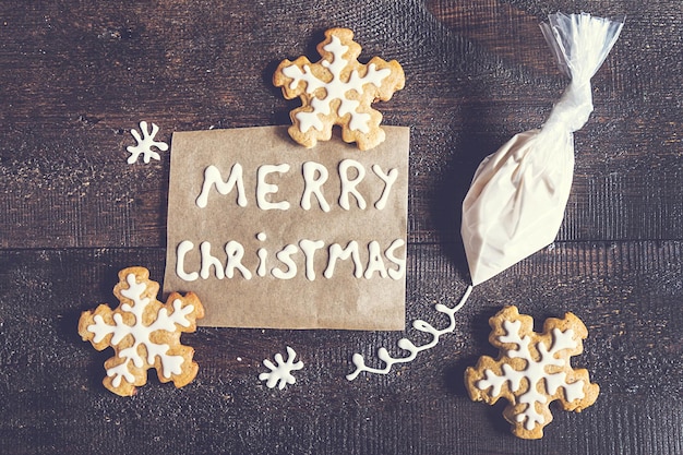 Inscripción de pan de jengibre de Navidad y una bolsa de azúcar glas sobre un fondo oscuro con efecto retro