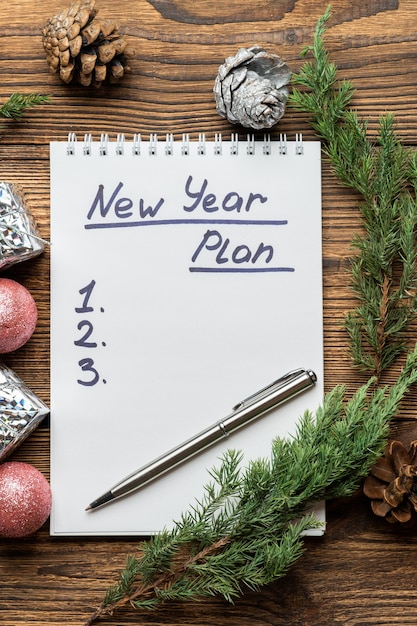 Inscripción de plan de año nuevo en cuaderno con abeto, ramas de abeto y juguetes de árbol de Navidad