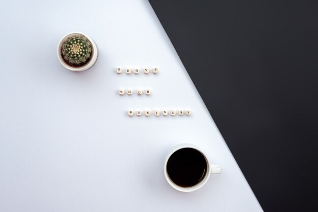 Una inscripción en su escritorio en el escritorio blanco y negro junto a un cactus y una taza de café.