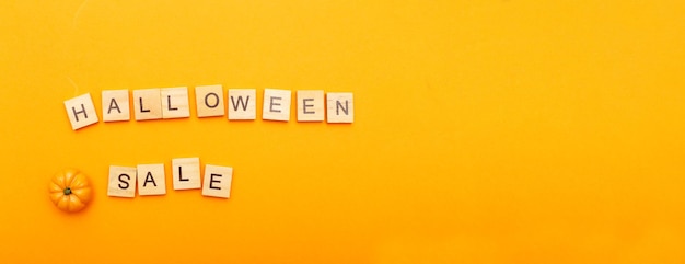 La inscripción venta de halloween con calabaza pequeña en banner de fondo naranja