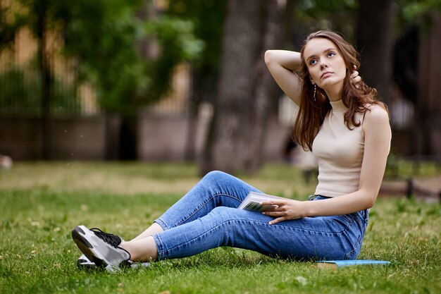 Inscrito hembra blanca se sienta en la hierba al aire libre en verano