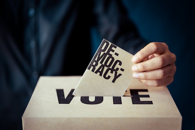 Inserto de papel marrón en la casilla de votación, concepto de democracia, tono retro