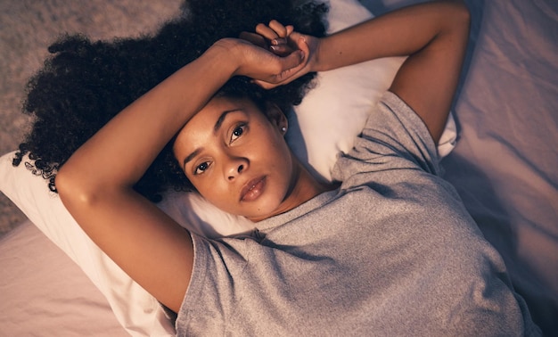 Foto insônia de retrato e noite com mulher no quarto por pensar em estresse e cansado de cima depressão de saúde mental e fadiga com pessoa se sentindo sozinha em casa por ansiedade frustrada e medo