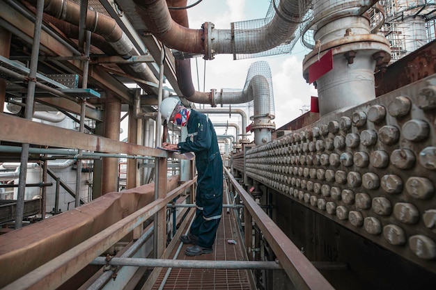 Foto inspeção do trabalhador masculino em tubos longos de aço e cotovelo de tubos no ventilador de barbatana da fábrica de óleo da estação durante a válvula da refinaria do trocador de calor da tubulação do registo de verificação visual