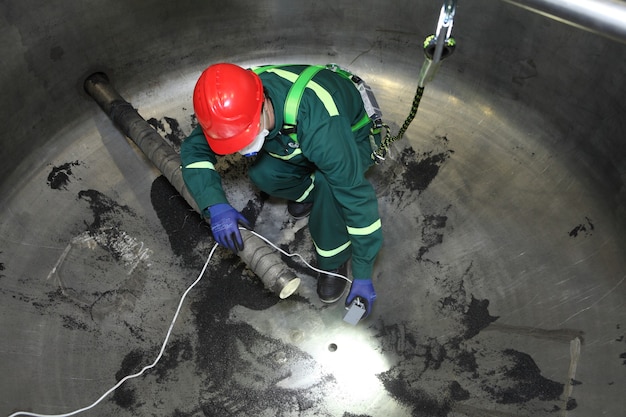 Inspeção interna da caldeira industrial, trabalhador está dentro da caldeira durante o reparo.