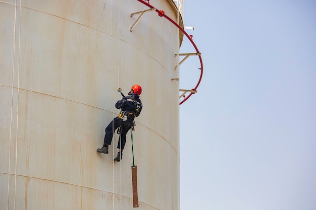 Inspección de acceso por cuerda de trabajador masculino del tanque de almacenamiento de espesor