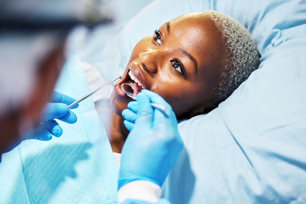 Inspección del dentista y mujer con herramientas en la boca en la clínica para el blanqueo de dientes de cavidad y ayuda mano para el dolor cirujano dental paciente africano y espejo para el examen de atención o comprobar la sonrisa saludable