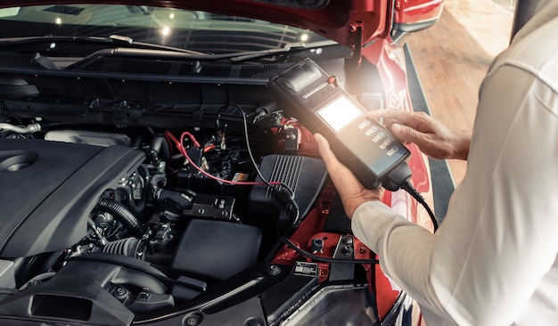 Inspección del hombre con el voltímetro del probador de capacidad de la batería. para el mantenimiento del servicio de reparación industrial a motor.