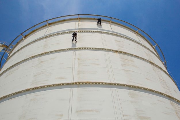 Inspección de seguridad de altura de acceso por cuerda de dos trabajadores masculinos de la industria de tanques de gas y petróleo de almacenamiento de espesor