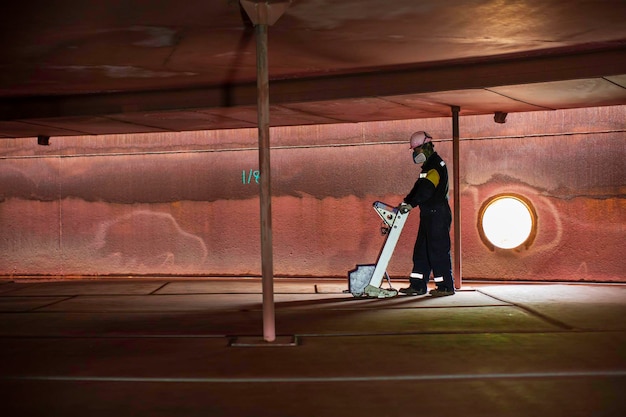 Inspección del trabajador masculino tanque de escaneo del piso flotante externo de la pared de óxido que pierde el espesor de la placa inferior para trabajar dentro del confinamiento
