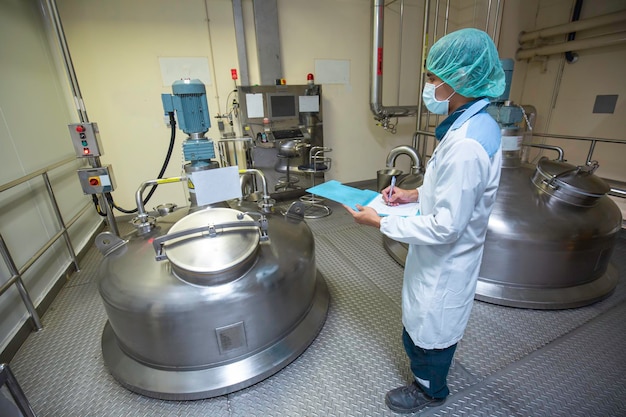 Inspección de trabajadores masculinos tanques de acero vertical inoxidable con tanque de equipo bodega química