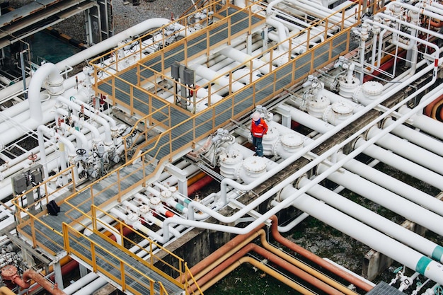 Inspección de trabajadores masculinos en tuberías largas de acero y codo de tubería en la fábrica de petróleo de la estación durante la válvula de refinería