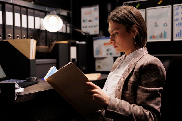 Foto inspector caucásico leyendo informe de criminología, trabajando horas extras en un caso criminal en la sala de archivos. detective privado analizando la evidencia de la escena del crimen, buscando nuevas pistas para atrapar al sospechoso