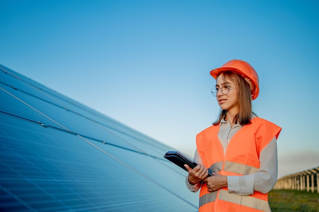 Inspector ingeniero mujer sosteniendo tableta digital trabajando en paneles solares power farm