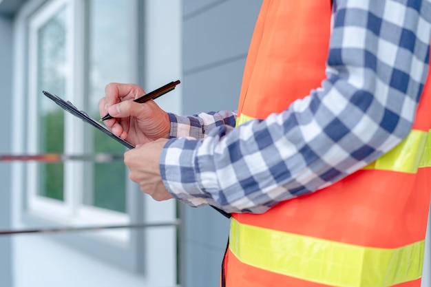 El inspector o ingeniero está inspeccionando e inspeccionando un edificio o una casa usando una lista de verificación Ingenieros y arquitectos o contratistas trabajan para construir la casa antes de entregársela al propietario