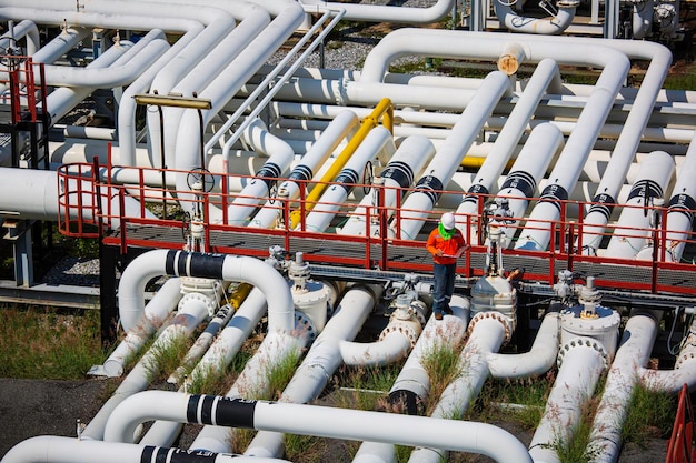 Inspektion durch männliche Arbeiter an langen Stahlrohren und Rohrbogenventilen in der Stationsölfabrik während des Raffinerieventils der visuellen Überprüfung des Pipelineöls