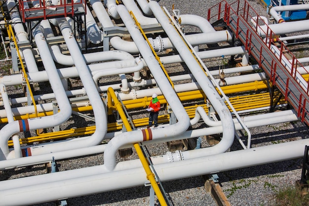 Inspektion von männlichen Arbeitern von oben an langen Stahlrohren und Rohrbogenventilen in der Stationsölfabrik während des Raffinerieventils der visuellen Überprüfung des Pipelineöls