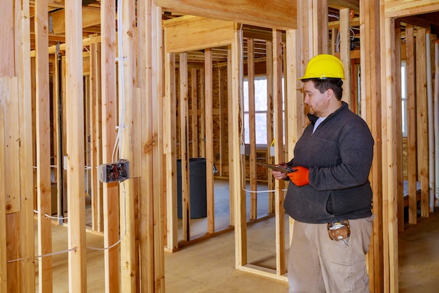 Inspektor mit gelbem Schutzhelm, der die elektrische Verkabelung im Haus überprüft