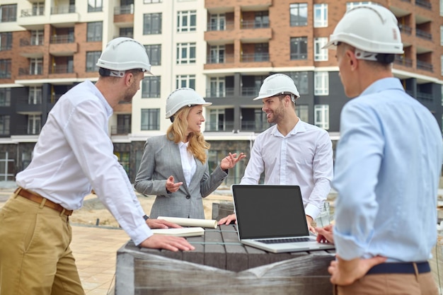 Inspetor amigável conversando com trabalhadores da construção civil ao ar livre