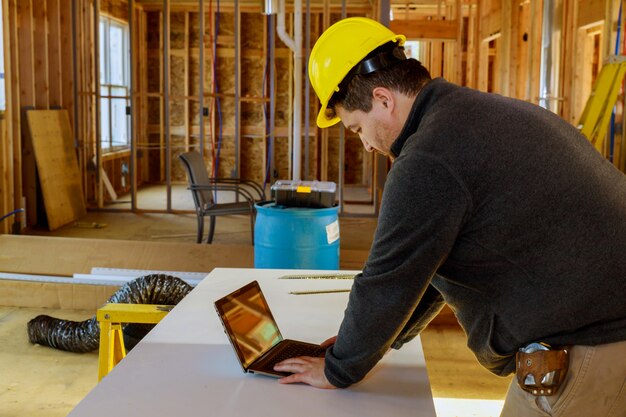 Inspetor com capacete amarelo e fita métrica e tablet no local de trabalho