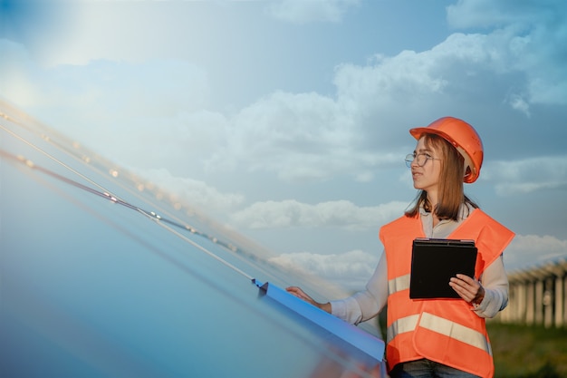 Inspetor engenheiro mulher segurando tablet digital trabalhando em painéis solares power farm, parque de células fotovoltaicas, conceito de energia verde.