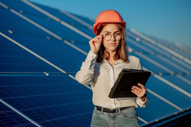 Foto inspetor engenheiro mulher segurando tablet digital trabalhando em painéis solares power farm