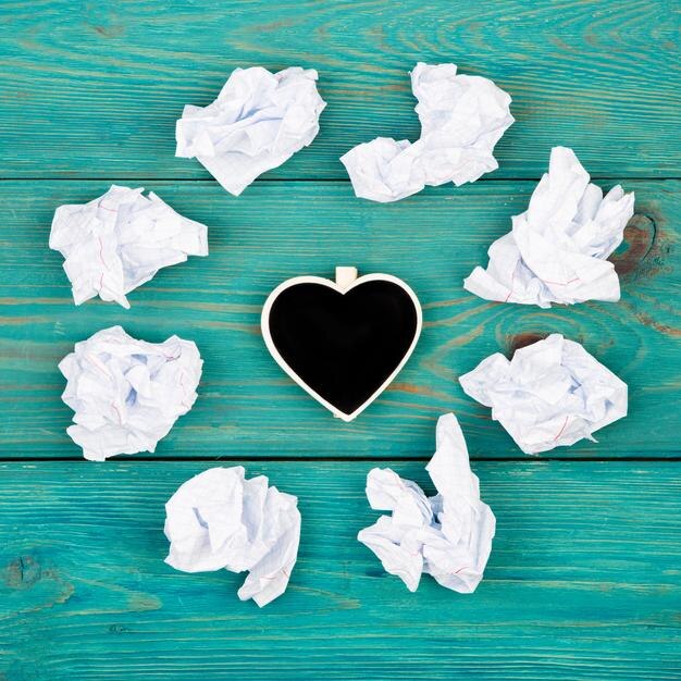 La inspiración del concepto de pensamiento elige las mejores ideas papel arrugado alrededor de la pizarra en forma de corazón