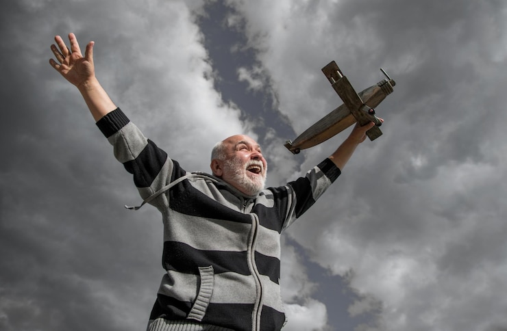 Foto inspiración senior jubilado hombre maduro en jubilación anciano sobre fondo de cielo con avión de juguete