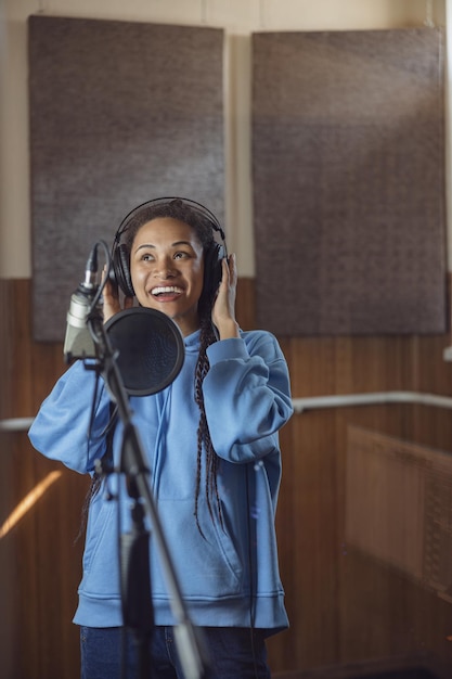 Inspirada jovem atriz africana cantora cantando ou expressando texto na sala à prova de som de um