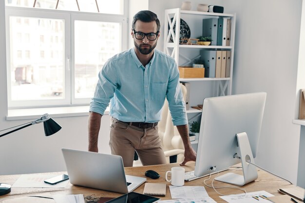 Foto inspirado para trabalhar duro. jovem empresário moderno olhando para a câmera enquanto trabalha no escritório