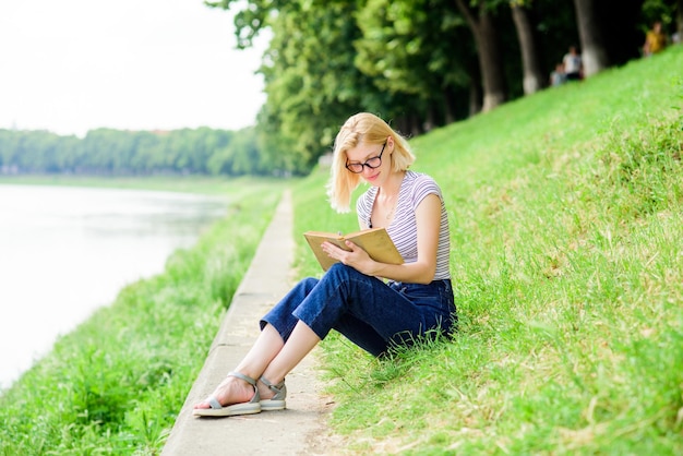 Inspirado pela história interessante do autor do romance Relaxe e obtenha novas informações, a leitura é meu hobby Estudo de verão mulher no parque lendo livro estudante com diário escolar para fazer anotações