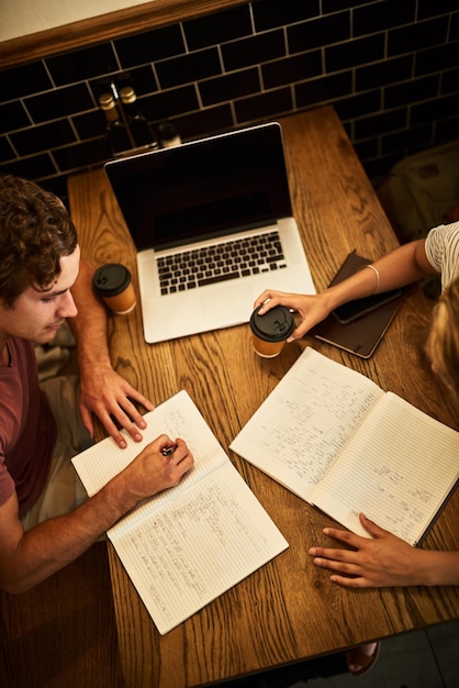 Inspirándonos unos a otros para estudiar más duro Toma en ángulo alto de dos estudiantes no identificables que tienen una sesión de estudio en una mesa de café