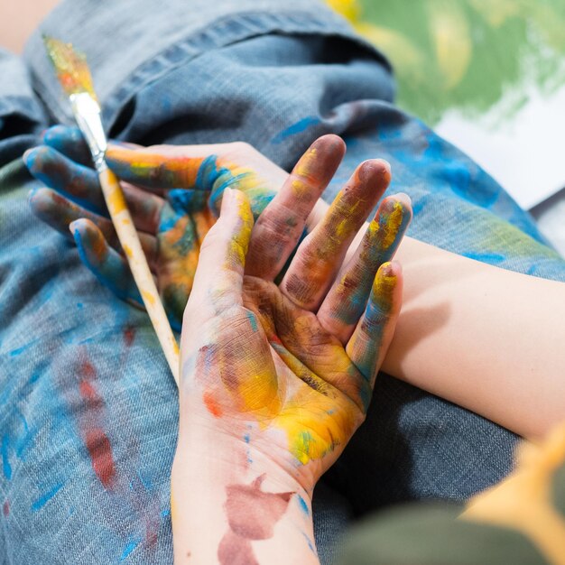 Inspiration und Kreativität Schnappschuss eines Künstlers, der eine Pause macht, während er mit Händen und Jeans sitzt, die mit bunter Farbe verschmutzt sind