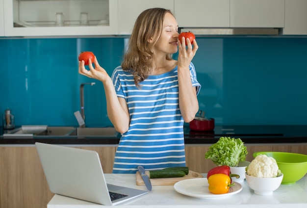 Inspirierte junge Frau, die Salat in der Küche kocht