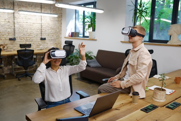 Inspirierter Mann und Frau, die im Büro eine VR-Brille tragen